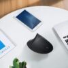 Ergonomic mouse on a table next to a phone and laptop